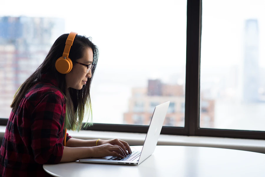 Woman working at a laptop beside a window