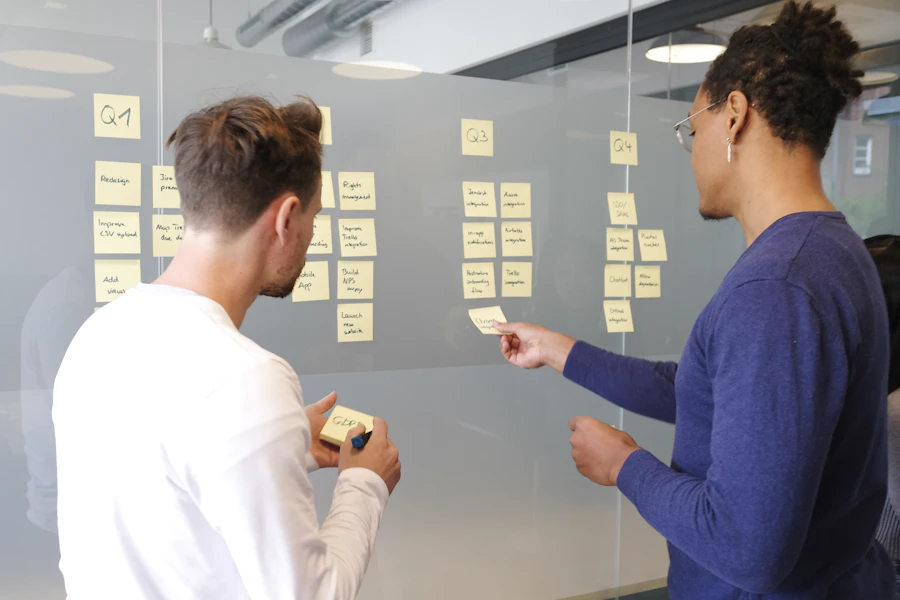 Two colleagues arranging a plan on a glass wall